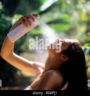 Junge Frau ihr Gesicht spritzen mit Wasser Zerstäuber, tropischen Garten, Guadeloupe, Französisch Westindien, Stockfoto