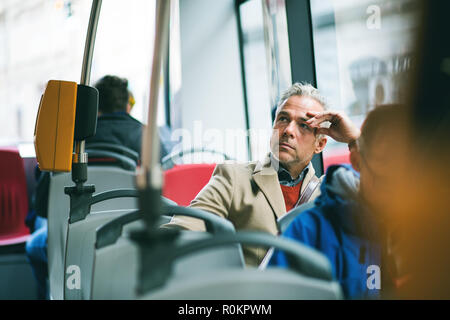 Müde reife Geschäftsmann mit dem Bus in der Stadt unterwegs. Stockfoto