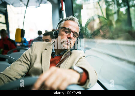 Reifen müde Geschäftsmann mit Kopfhörer mit dem Bus in der Stadt unterwegs. Stockfoto