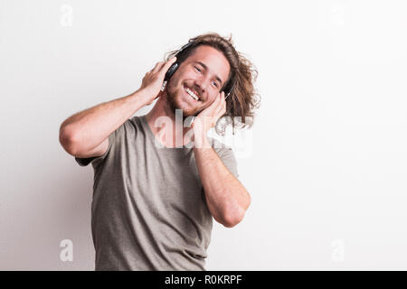 Porträt einer fröhlichen jungen Mann mit Kopfhörern in einem Studio.
