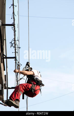 Belgrad, Serbien - November 19, 2018: industriekletterer am Seil hängend während der Installation von Werbebanner auf einer Bilding, Low Angle View Stockfoto