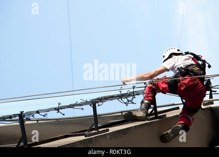 Belgrad, Serbien - November 19, 2018: industriekletterer am Seil hängend während der Installation von Werbebanner auf einer Bilding, Low Angle View Stockfoto