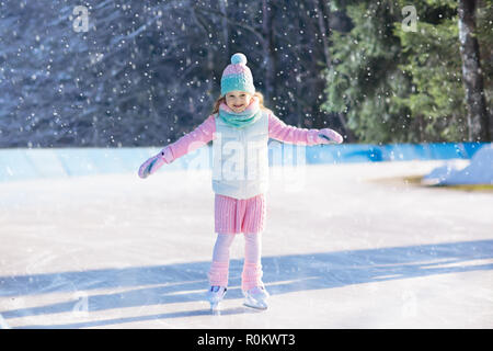 Kind Schlittschuhlaufen auf Natureis auf sonnigen Wintertag. Kinder mit Schlittschuhen. Kleines Mädchen Schlittschuhlaufen auf zugefrorenen See in Snowy Park. Schnee und Winter Spaß. Gesunde heraus Stockfoto