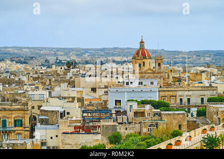 Die rote Kuppel von St. George Kirche über den Dächern von Victoria, Insel Gozo, Malta steigt. Stockfoto