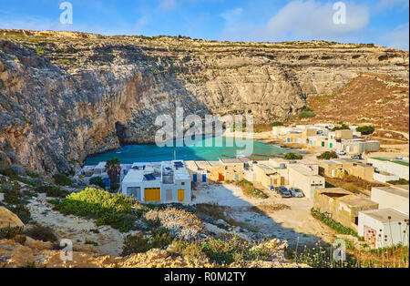 Der felsigen Klippe ist der beste Ort die kleine San Lawrenz Fischerdorf am Ufer der Dwejra Binnenmeer, Insel Gozo, Ma entfernt zu übersehen Stockfoto