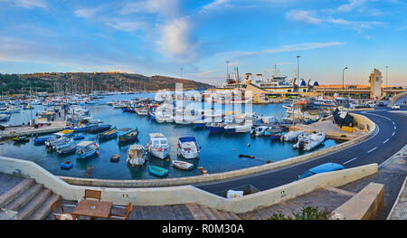 GHAJNSIELEM, MALTA - 15. JUNI 2018: Panorama der Hafen von Mgarr mit zahlreichen Fischen Boote, Yachten und Fähren Terminal auf Hintergrund, am 15. Juni in Stockfoto