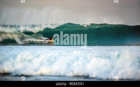 Surfer aufsteht auf einer Welle. Die Welle dreht sich mit Schaum und Spritzer. Stockfoto