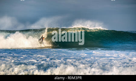 Surfer aufsteht auf einer Welle. Die Welle dreht sich mit Schaum und Spritzer. Stockfoto