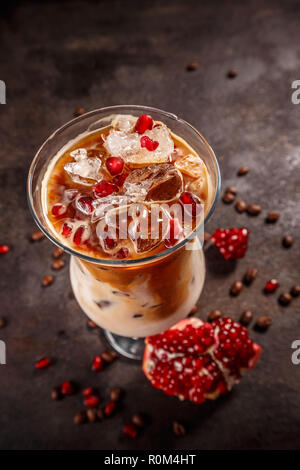 Eiskaffee mit Milch in hohes Glas aromatisiert mit Granatapfel Sirup Stockfoto