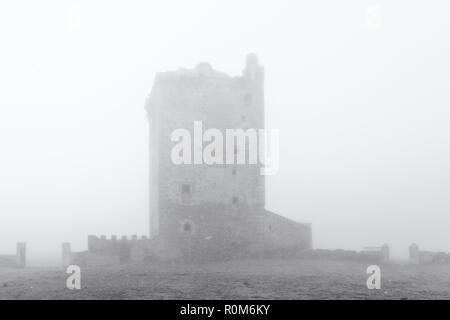 Turm der Mogollones. Landschaft mit einem mittelalterlichen Turm in Nebel gehüllt. Der Extremadura. Spanien. Stockfoto