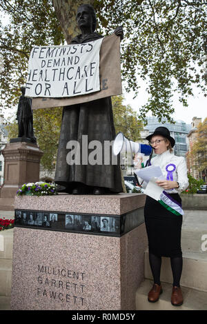 London, Großbritannien. 6. November 2018. Aktivisten aus feministischen Fightback gekleidet als Suffragetten das Zeichen auf der neuen Millicent Fawcett Statue in Parliament Square von "Mut fordert Mut Überall' zu 'Feministinnen nachfrage Gesundheitsversorgung für alle" gegen NHS Gebühren für Migranten ändern. Im Rahmen der neuen NHS Ladesystem, Migranten nicht als "auf Dauer ansässig" in Großbritannien sind aufgeladen wird bis 7000 für Schwangerschaft Pflege und £ 1300 für eine Abtreibung in einem NHS Hospital £. Credit: Mark Kerrison/Alamy leben Nachrichten Stockfoto