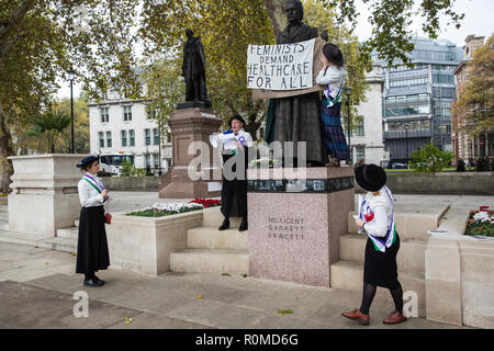 London, Großbritannien. 6. November 2018. Aktivisten aus feministischen Fightback gekleidet als Suffragetten das Zeichen auf der neuen Millicent Fawcett Statue in Parliament Square von "Mut fordert Mut Überall' zu 'Feministinnen nachfrage Gesundheitsversorgung für alle" gegen NHS Gebühren für Migranten ändern. Im Rahmen der neuen NHS Ladesystem, Migranten nicht als "auf Dauer ansässig" in Großbritannien sind aufgeladen wird bis 7000 für Schwangerschaft Pflege und £ 1300 für eine Abtreibung in einem NHS Hospital £. Credit: Mark Kerrison/Alamy leben Nachrichten Stockfoto