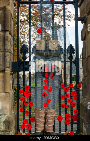 Haddington, East Lothian, Schottland, Vereinigtes Königreich, 6. November. UK Wetter: Sonnenschein bei St Marys" Pfarrkirche, wo ein handcrafted Soldat von Chicken Wire Mesh mit Mohn verziert wacht an der Pforte Stockfoto