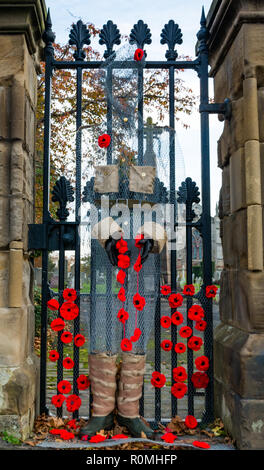 Haddington, East Lothian, Schottland, Vereinigtes Königreich, 6. November. UK Wetter: Sonnenschein bei St Marys" Pfarrkirche, wo ein handcrafted Soldat von Chicken Wire Mesh mit Mohn verziert wacht an der Pforte Stockfoto