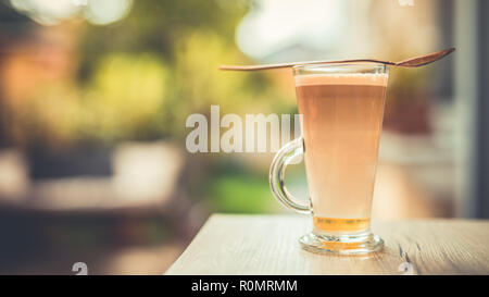 Entspannende morgendliche closeup, Kaffee auf hölzernen Tischplatte in langen Glas. Latte für morgen Motivation und Tag starten. Stockfoto