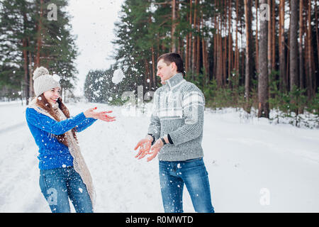 Schneeballschlacht. Winter-Paare, die Spaß im Schnee im Freien spielen. Junge fröhliche multiethnische Brautpaar. Stockfoto