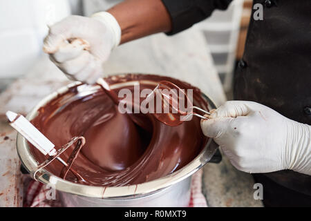 Arbeitnehmer vorsichtig rühren, geschmolzene Schokolade in eine Schüssel geben. Stockfoto