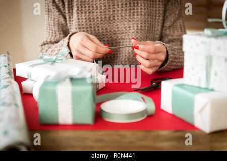 DIY Geschenkverpackung. Nicht erkennbare Frau Verpackung schöne Weihnachtsgeschenke im nordischen Stil. Die Hände schließen. Stockfoto
