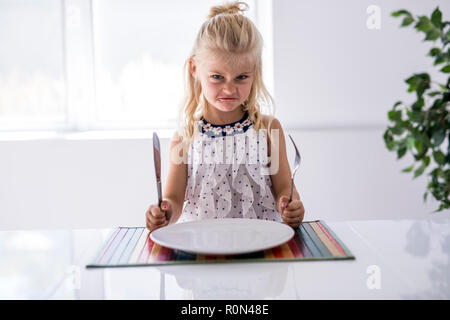 Ein wütendes Mädchen warten auf das Abendessen. Mit einer Gabel in der Hand Stockfoto