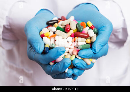 Indische Arzt trägt blaue Chirurgische Latexhandschuhe holding Handvoll Pillen auf weißem Hintergrund isoliert Stockfoto