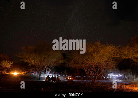 Männer lernen durch ein Feuer, wie Sie trinken ein hausgemachtes Brauen in einem pokot Gemeinschaft der Hirten in Baringo County, Kenia, 1. Oktober 2018. Stockfoto