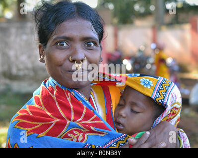 Junge indische Adivasi Frau (Dongria Kondh Stammes) mit ausgeprägten tribal Nase Schmuck hält ein schlafendes Baby in ihren Armen. Stockfoto