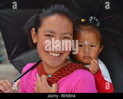 Junge indische Monpa Bergvolk Frau trägt Ihr Kleinkind Mädchen in einem traditionellen Babytragetuch auf ihrem Rücken. Stockfoto