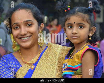 Herausgeputzt, jungen malaysischen indische Frau mit ihrer kleinen Tochter lächelt während Thaipusam. Stockfoto