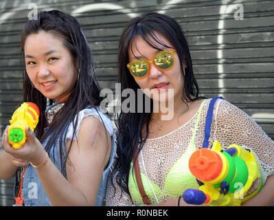 Zwei Trigger-happy Koreanische junge Frauen mit großen Wasserpistolen während des Songkran Water Festival in Bangkok. Stockfoto