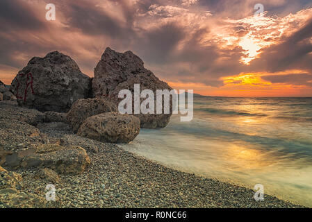 Lange Belichtung photograhy am felsigen Kato Petres Strand Landschaft in der Abenddämmerung. Rhodos, Griechenland Stockfoto