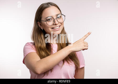 Gerne tolle junge Frau zeigt mit dem Finger auf die Kopie Raum Stockfoto