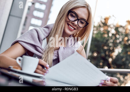 Attraktive Frau das Lesen von Zeitungen im City Cafe Stockfoto