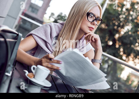 Attraktive Frau das Lesen von Zeitungen im City Cafe Stockfoto