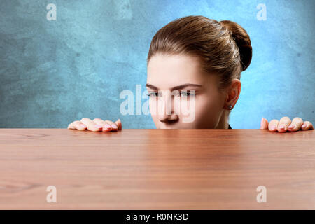 Frau lugen unter dem Rand der hölzernen Tisch. Stockfoto