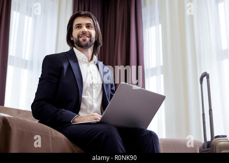 Freudige smart stattlichen Unternehmer sitzen auf dem Bett Stockfoto