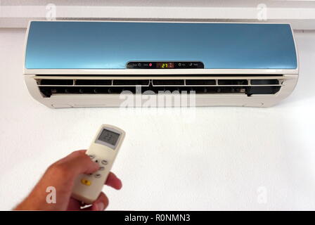 Jemand Ändern der Einstellungen eines inländischen AC oder Klimaanlage mit Fernbedienung - Fokus auf die Wandhalterung - Kopieren Platz für Text Stockfoto