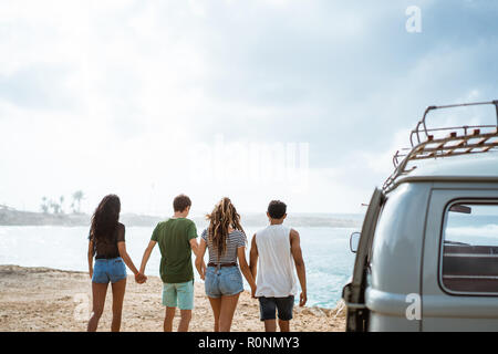 Freunde halten sich an den Händen und Laufen am Strand an einem sonnigen Tag Stockfoto