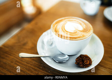 Tasse mit heißem lecker Kaffee auf hölzernen Tisch im Cafe, in der Nähe Stockfoto