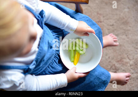 Junge Baby Kleinkind Mädchen im Alter von 2 Jahren essen gesunde Ernährung von frischem Paprika und Gurken snack Foto aufgenommen von Simon Dack Stockfoto