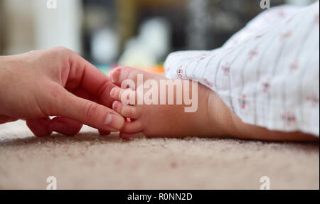 Junge Baby Kleinkind Mädchen im Alter von zwei Jahren Nahaufnahme füsse Zehen mit Müttern Hände und Finger Stockfoto