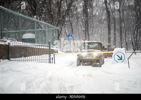 SUV-Auto gestoppt bei automatischer Eintrag Tor während starker Schneefall. Fahrzeug Access Gateway System. Staffel von Blizzard auf der winer auf Straße der Stadt. Stockfoto