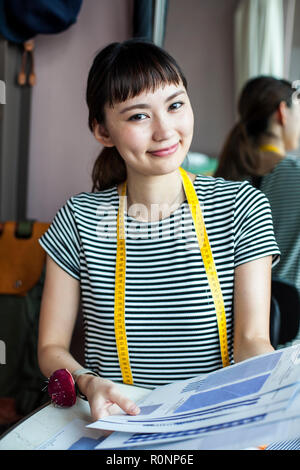Japanische Frauen Mode Designer arbeiten in ihrem Atelier, in die Kamera lächeln. Stockfoto