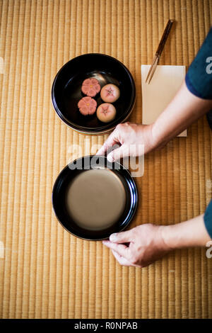 Hohen winkel Nahaufnahme von Mann knelling am Boden, und halte eine Schüssel mit Süßigkeiten Wagashi, traditionell während einer japanischen Teezeremonie serviert. Stockfoto