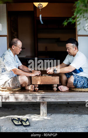 Zwei japanische Männer sitzen auf dem Boden auf der Veranda der traditionellen japanischen Haus, Spielen gehen. Stockfoto