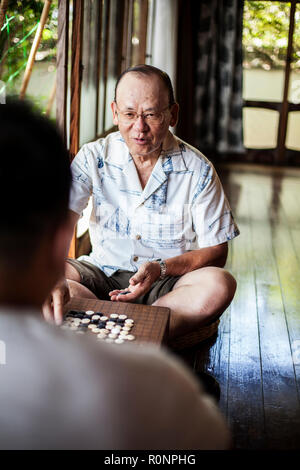Zwei japanische Männer sitzen auf dem Boden auf der Veranda der traditionellen japanischen Haus, Spielen gehen. Stockfoto