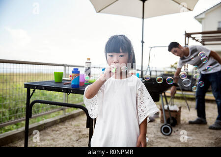 Portrait von japanischen Mädchen mit weißem T-Shirt bläst Seifenblasen. Stockfoto