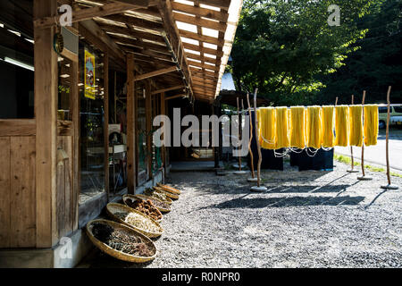 Außenansicht von textilen Pflanzenfarbstoff Workshop, mit gelbem stoff hängen zum Trocknen in die Sonne und Körbe mit Pflanzenfarben. Stockfoto