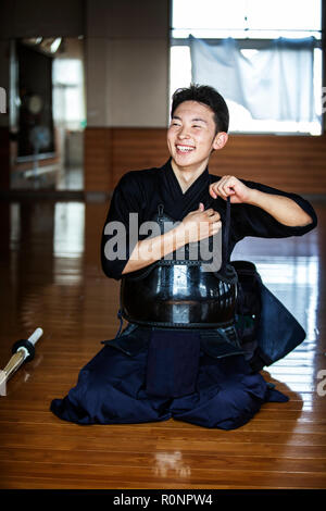 Männliche japanische Kendo Kämpfer kniet auf dem Boden, seinen Brustpanzer befestigen. Stockfoto