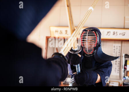 Zwei japanische Kendo Kendo Kämpfer tragen Masken üben mit Holz Schwert in der Turnhalle. Stockfoto