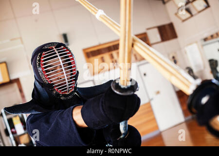 Zwei japanische Kendo Kendo Kämpfer tragen Masken üben mit Holz Schwert in der Turnhalle. Stockfoto